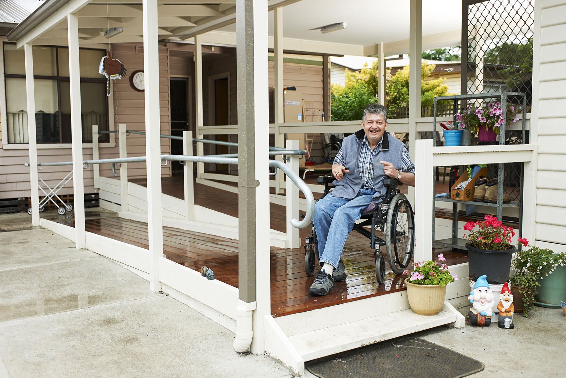 Smiling man in wheelchair on accessible ramp entrane to home